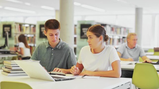  Female college student working on a project with a male student in the school library
