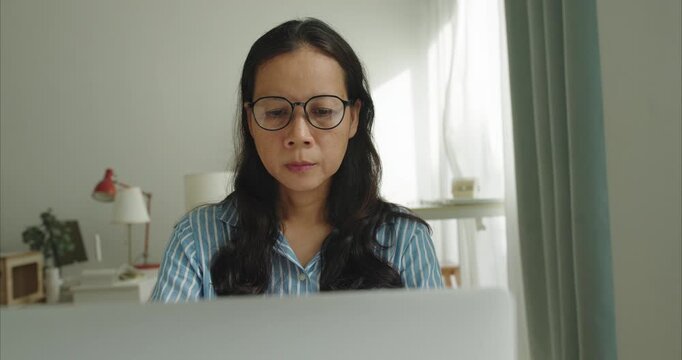 Asian middle woman wear glasses using laptop at home office