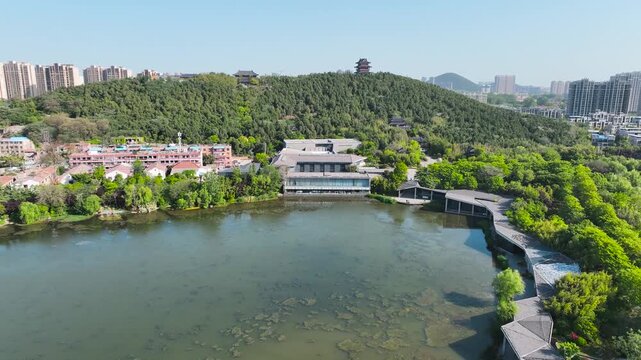 Aerial view of urban lake and forested hill with traditional Chinese pavilions in China