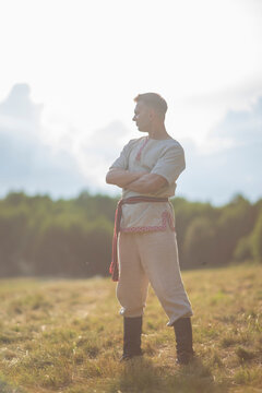 Strong young slavic man with crossed arms posing at summer field with copy space
