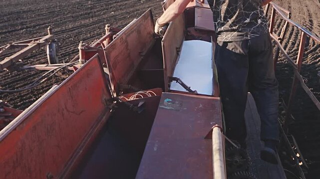 Filling grain seeder hoppers with granular nitrogen fertilizer before spring planting on agricultural field