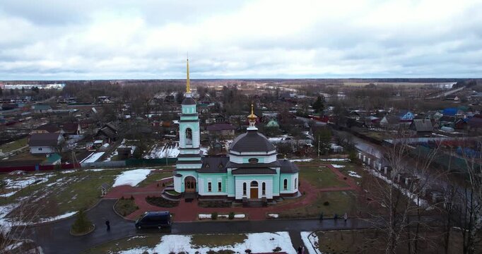 Aerial wide establishing shot of a beautiful light blue Russian Orthodox church in the rural village of Dmitrova Gora during early spring, Tver Region