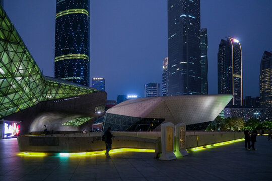 Guangzhou, China - 24 February 2024: View of the futuristic Guangzhou Opera House architecture illuminated at night with surrounding skyscrapers and modern urban plaza.