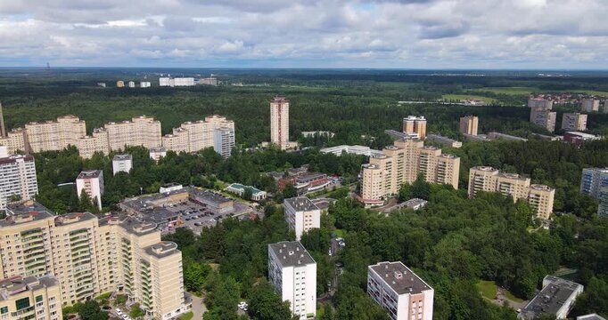 Aerial forward flying shot over a densely populated microrayon showing diverse apartment buildings nestled among dense green forests