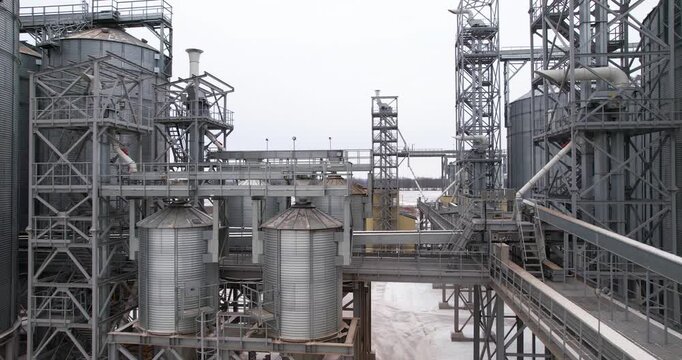Aerial forward flying shot of a massive industrial grain elevator complex surrounded by a winter landscape