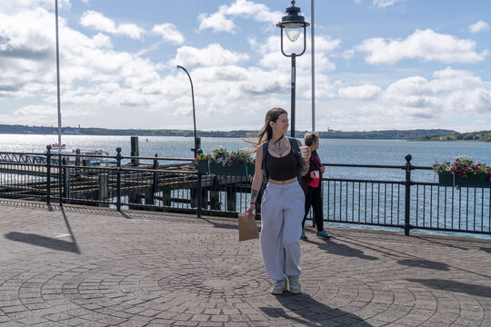 Woman enjoying coffee on boardwalk along bay