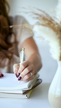Woman with manicured nails writing in a spiral notebook