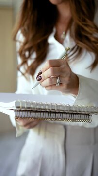 Elegant woman writing in a spiral bound notebook