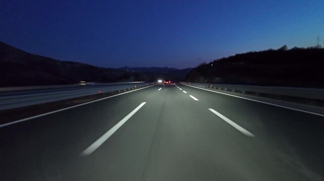 POV driving on modern highway with bright lights illuminating the road at night. Transportation, travel and infrastructure concept, 4k