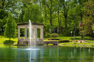 Naklejka premium Classic stone pavilion and a water fountain spraying in a pond