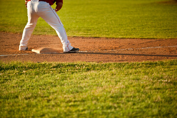Naklejka premium Rear view of a baseball player standing on a base during a game