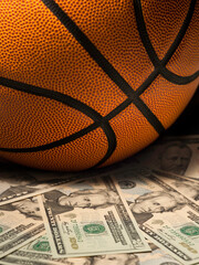 Naklejka premium Basketball gambling concept on a pile of US dollar bills