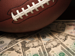 Naklejka premium Football gambling concept on a pile of US dollar bills