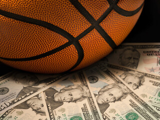 Naklejka premium Basketball gambling concept on a pile of US dollar bills