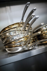 Fototapeta premium Stack of stainless steel frying pans on a kitchen shelf