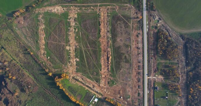 Top-down aerial panorama of a massive land clearing and earthworks site with parallel trenches next to a highway