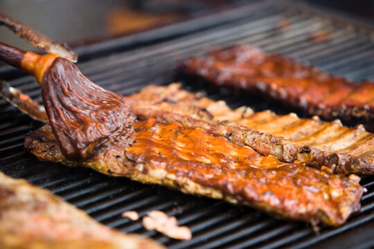Close up of slabs of barbecue ribs cooking on a large outdoor grill