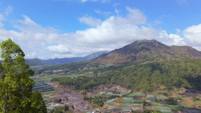 Panoramic view of Mount Batur caldera with agricultural fields and green hills in Bali, Indonesia