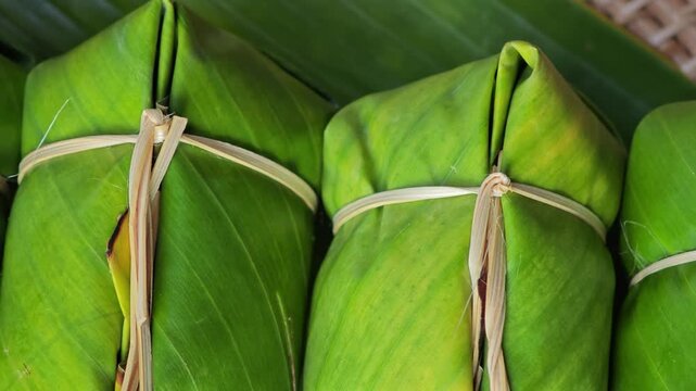 Thai dessert made of sticky rice, banana and coconut milk, all wrapped in banana leaves.