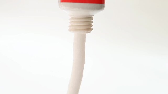 White cream coming out of a tube on white background, medical, cosmetic or skincare product