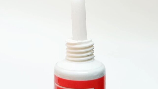 White cream coming out of a tube on white background, medical, cosmetic or skincare product