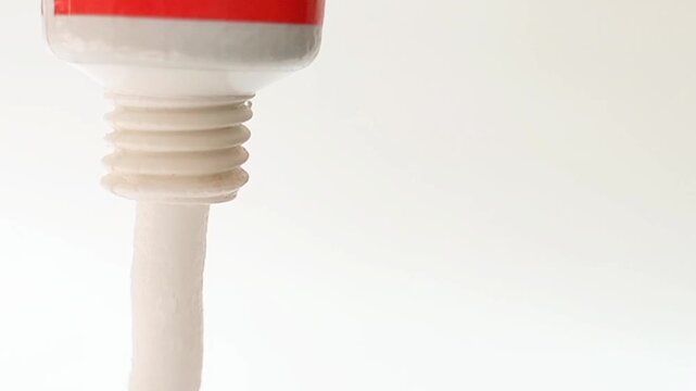 White cream coming out of a tube on white background, medical, cosmetic or skincare product. close up