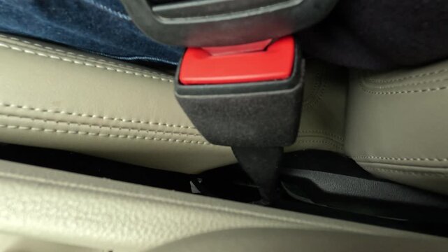 Close-up footage of a person fastening a seat belt inside a vehicle before starting a journey. The safety belt clicks securely into place, highlighting responsible driving habits, road safety awarenes