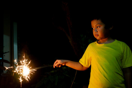 Young Asian Boy Holding Bright Sparkler Firework at Night