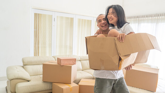 Laughing Young Couple Playing with Cardboard Box While Moving Into New Home
