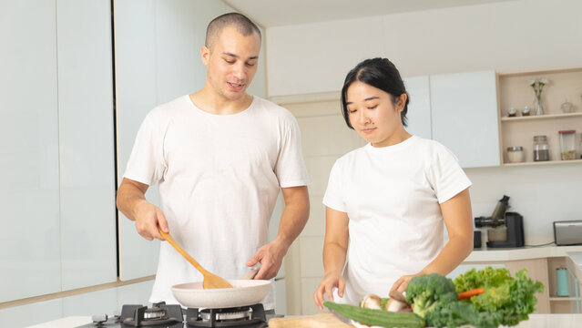Happy Young Couple Cooking Healthy Meal Together in Modern Bright Kitchen