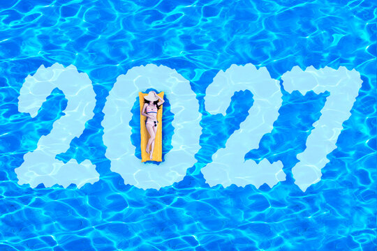 High Angle View of Woman on Inflatable Mattress Inside 2027 Text in Swimming Pool