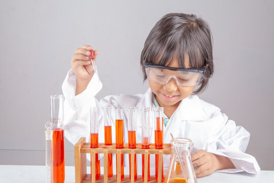 Cute Little Asian Girl in Lab Coat Doing Science Experiment with Test Tubes