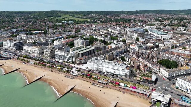 Cinematic aerial drone flyover from Eastbourne Pier and beach into Eastbourne town centre, showcasing busy shopping streets, seafront and vibrant coastal tourism in 4K.
