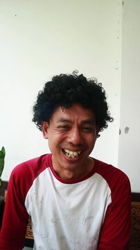 An Indonesian man makes an ugly funny face with a cheerful expression in a casual setting