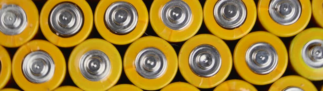 Yellow aa alkaline batteries rotating in a repeating pattern supplying electricity for various consumer electronics.