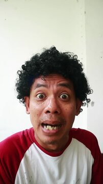 An Indonesian man makes an ugly funny face with a white background