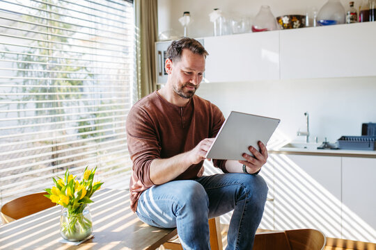 Man using smart home app to control electric window shades indoors.