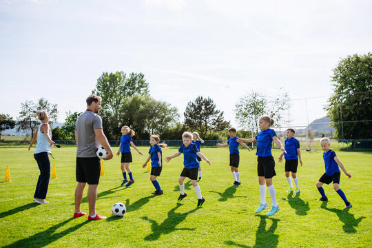 Young football players warming up before training session on pitch.