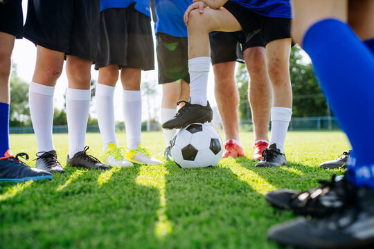 Youth football team gathering around soccer ball before training session.