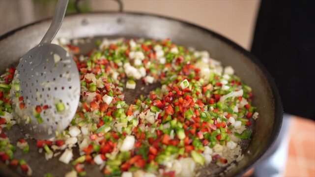 Chef cooking spanish paella with chopped vegetables