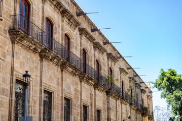 Fototapeta premium Historic Colonial Stone Building with Balconies and Ornate Facade Under Blue Sky