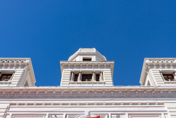 Fototapeta premium Historic White Neoclassical Facade with Tower Elements Under Deep Blue Sky