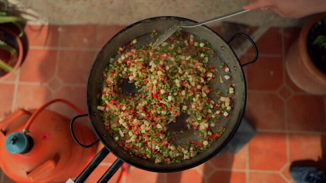 Chef cooking spanish paella sofrito outdoors