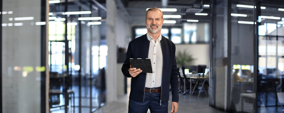 Modern business man in formalwear using digital tablet while standing in the office