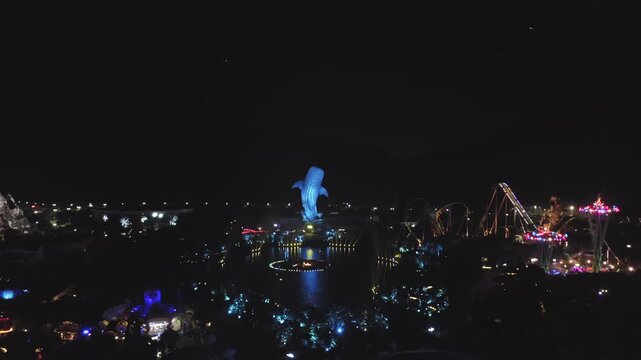 Illuminated amusement park at night with roller coasters and colorful rides