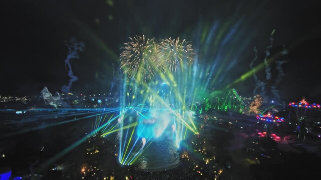Night fireworks over amusement park lagoon and roller coasters