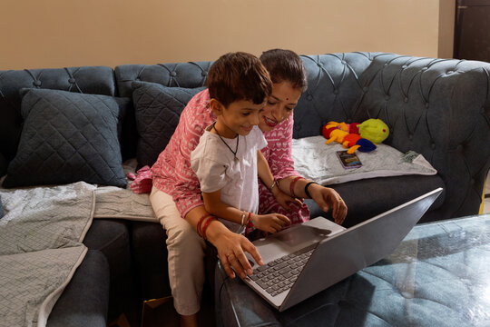 Mother and son using a laptop together in the living room