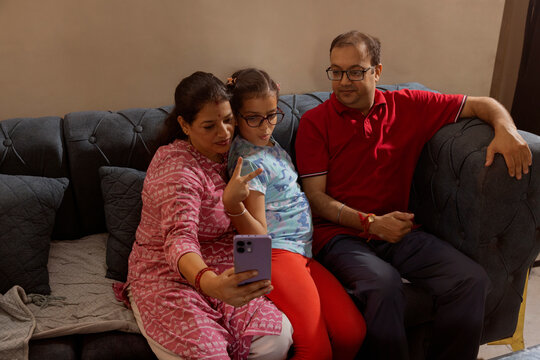 mother taking selfie with her husband and daughter posing