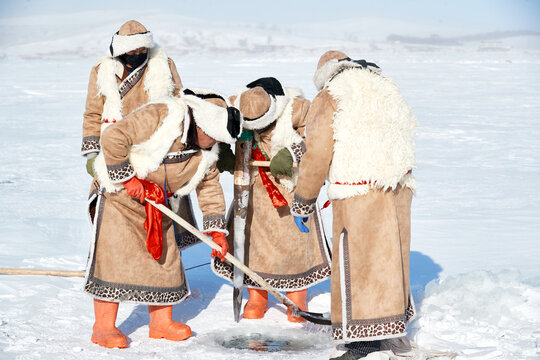 People ice-fishing on the frozen lake during the cold winter.