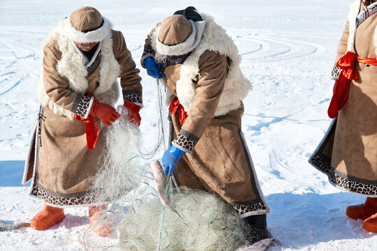 People ice-fishing on the frozen lake during the cold winter.